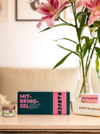 Mitbringsel Geschenkbox mit Brot und Blumen auf einem hellen Tisch