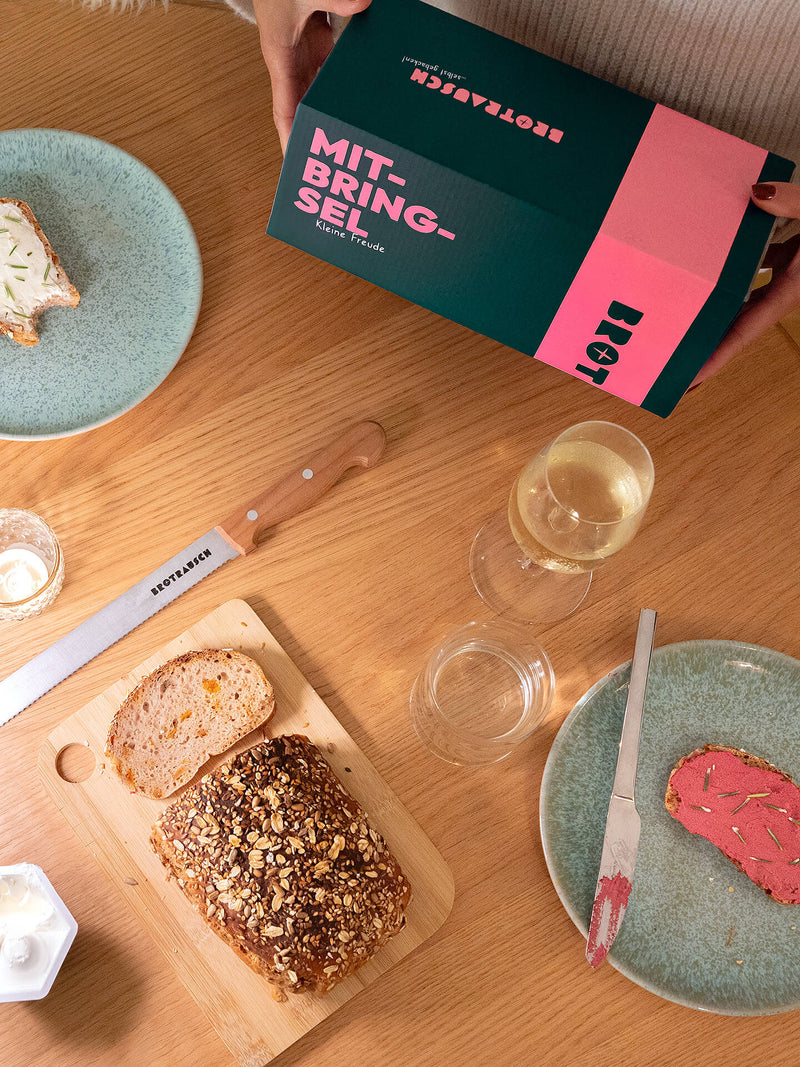 Gedeckter Frühstückstisch mit selbstgebackenem Brot und Mitbringsel Geschenkbox, Draufsicht
