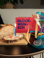 Glückwunsch Geschenkbox auf dem Tisch neben Geburtstagskuchen und selbstgebackenem Brot