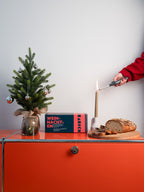 Brotrausch Weihnachtsbox und frisch gebackenes Brot auf dem Sideboard, daneben wird eine Kerze angezündet