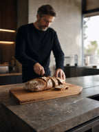 Mann schneidet selbst gebackenes Brot auf dem Brotrausch x Puuuro Brotschneidebrett in moderner Küche