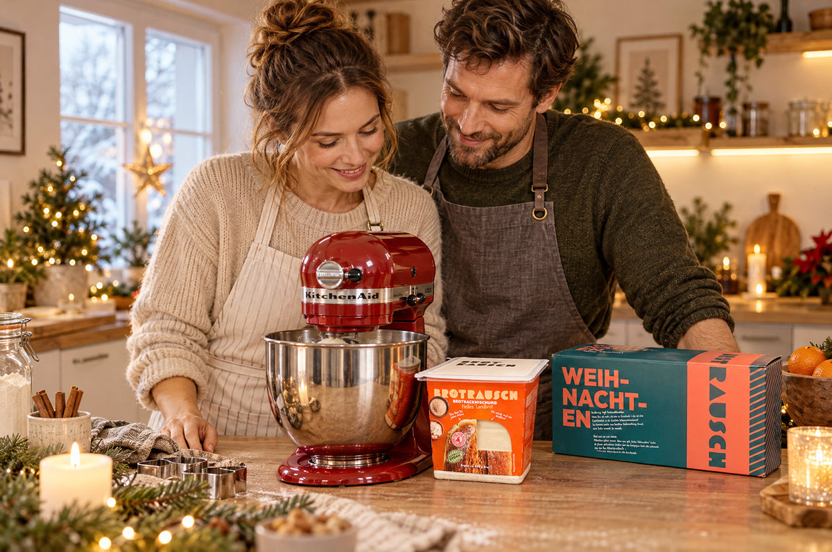 Paar backt gemeinsam in der weihnachtlichen Küche mit Brotbackmischung Helles Landbrot und Brotrausch Geschenkbox